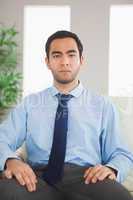 Serious classy businessman sitting on cosy sofa