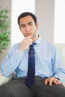 Young classy businessman thinking on cosy sofa