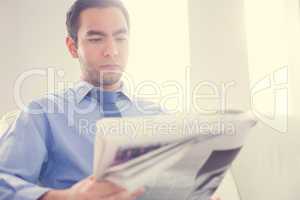 Serious handsome businessman reading newspaper