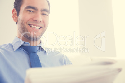 Laughing man looking at camera and reading a newspaper