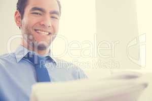 Laughing man looking at camera and reading a newspaper