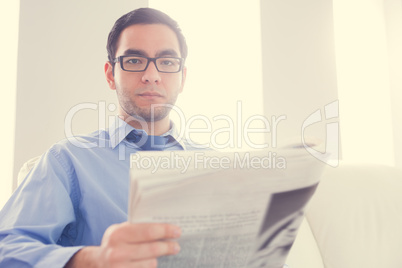 Frowning man looking at camera and holding a newspaper