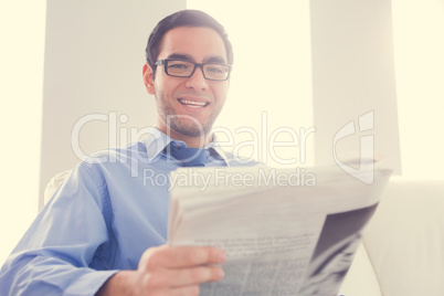 Happy man looking at camera and holding a newspaper