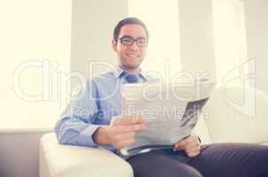 Pleased man looking at camera and holding a newspaper sitting on