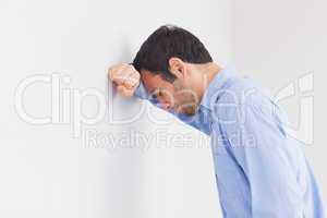 Upset man leaning his head against a wall