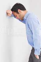 Worried man leaning his head against a wall