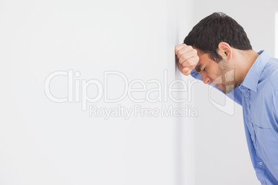 Angry man leaning his head against a wall