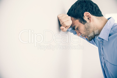 Depressed man leaning his head against a wall
