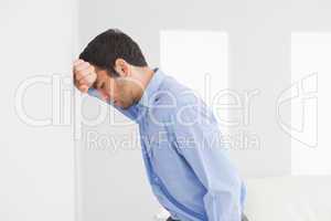 Sad man leaning his head against a wall