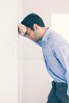 Devastated man leaning his head against a wall