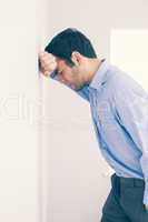 Devastated man leaning his head against a wall