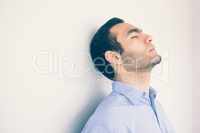 Thoughtful man leaning against a wall