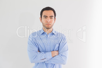 Serious man standing with arms crossed and looking at camera