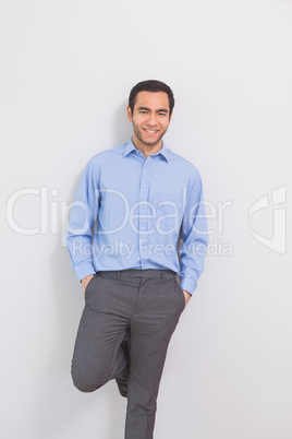 Pleased man leaning against a wall hands in the pockets