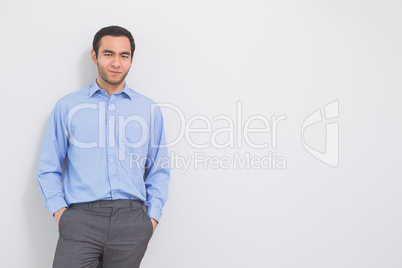 Content man leaning against a wall hands in the pockets