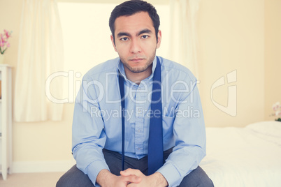 Serious man sitting on his bed