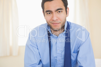 Relaxed man smiling at camera sitting on a bed