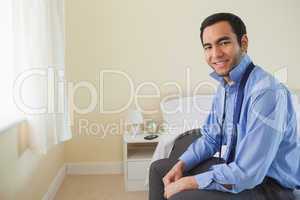 Pleased man looking at camera and relaxing sitting on his bed