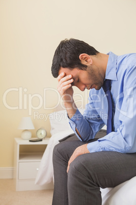 Upset man sitting head in hands on his bed