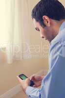 Close up of a man using a mobile phone sitting on a bed
