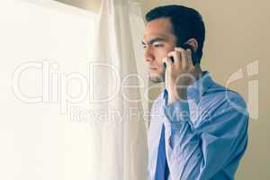 Irritated man calling someone with a mobile phone and looking ou