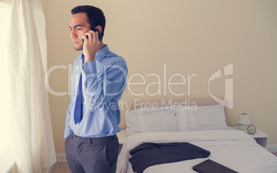 Stressed man calling someone with a mobile phone and looking out