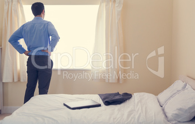 Rear view of a man standing in front of a window and looking out