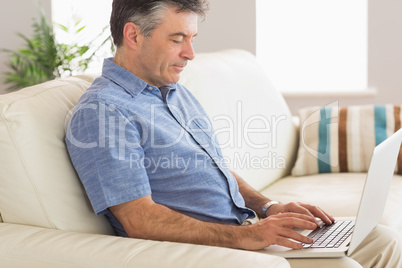Thinking man sitting on sofa using laptop