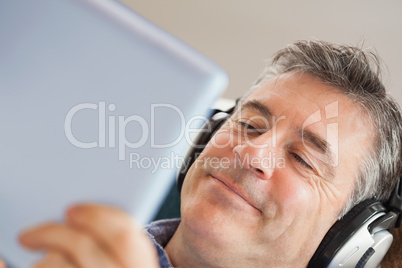 Smiling man listening music and using a tablet pc Smiling man listening music and using a tablet pc