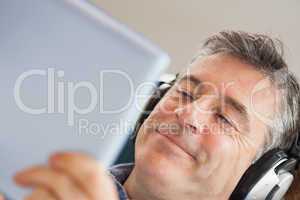 Smiling man listening music and using a tablet pc