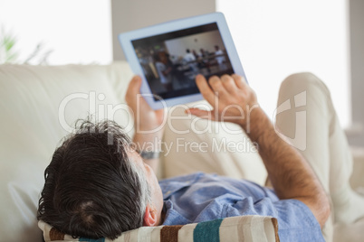 Man laying on a sofa using a tablet pc