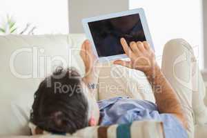 Man laying on a sofa using a tablet pc
