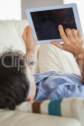 Man laying on a sofa using a tablet pc