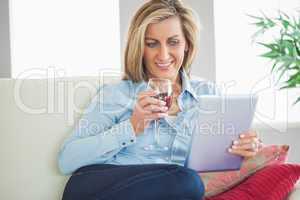 Smiling woman drinking wine and using a tablet pc