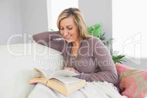 Smiling woman reading a book on a sofa