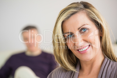 Smiling woman with her husband in the background