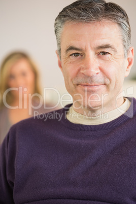 Smiling man with his wife in the background