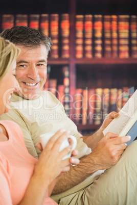 Happy couple reading books and drinking coffee in a reading room