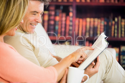 Happy couple reading a book in a reading room and drinking coffe