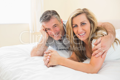 Happy couple lying on a bed looking at camera Happy couple lying on a bed looking at camera