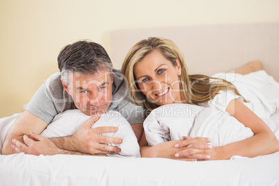 Happy couple lying on a bed and looking at camera