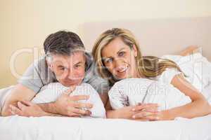 Happy couple lying on a bed and looking at camera