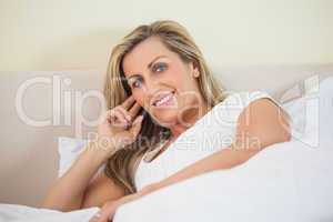 Smiling woman lying on a bed looking at camera