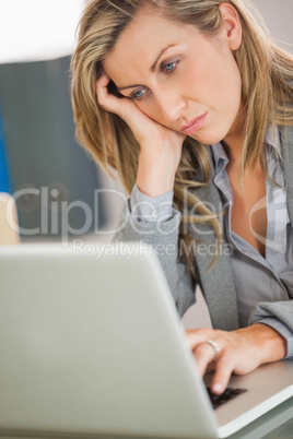 Jaded businesswoman looking at her laptop in an office
