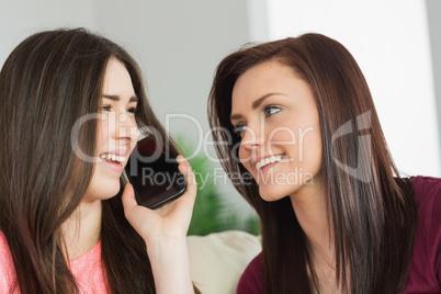 Two happy girls calling someone with a mobile phone