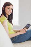 Cheerful girl sitting on a sofa using a tablet pc