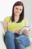 Relaxed girl sitting on a sofa using a tablet pc