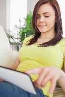 Smiling happy girl using a tablet pc sitting on a sofa