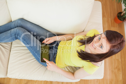 Brunette using a tablet pc on a sofa