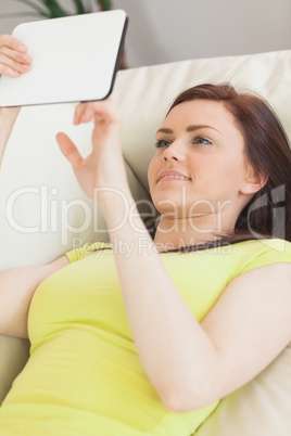 Cheerful teen lying on a sofa using a tablet pc